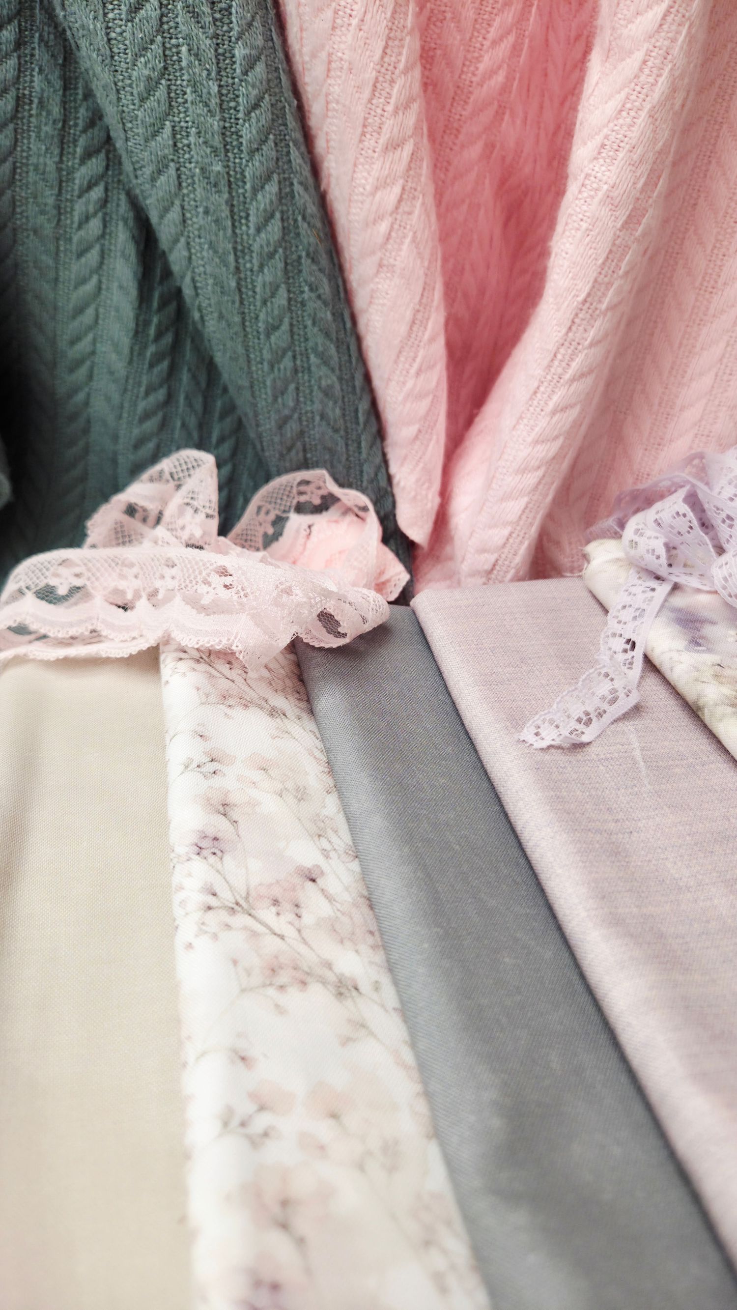 Soft pink, gray, and floral fabric swatches with delicate lace trim displayed together, ideal for sewing or crafting projects.