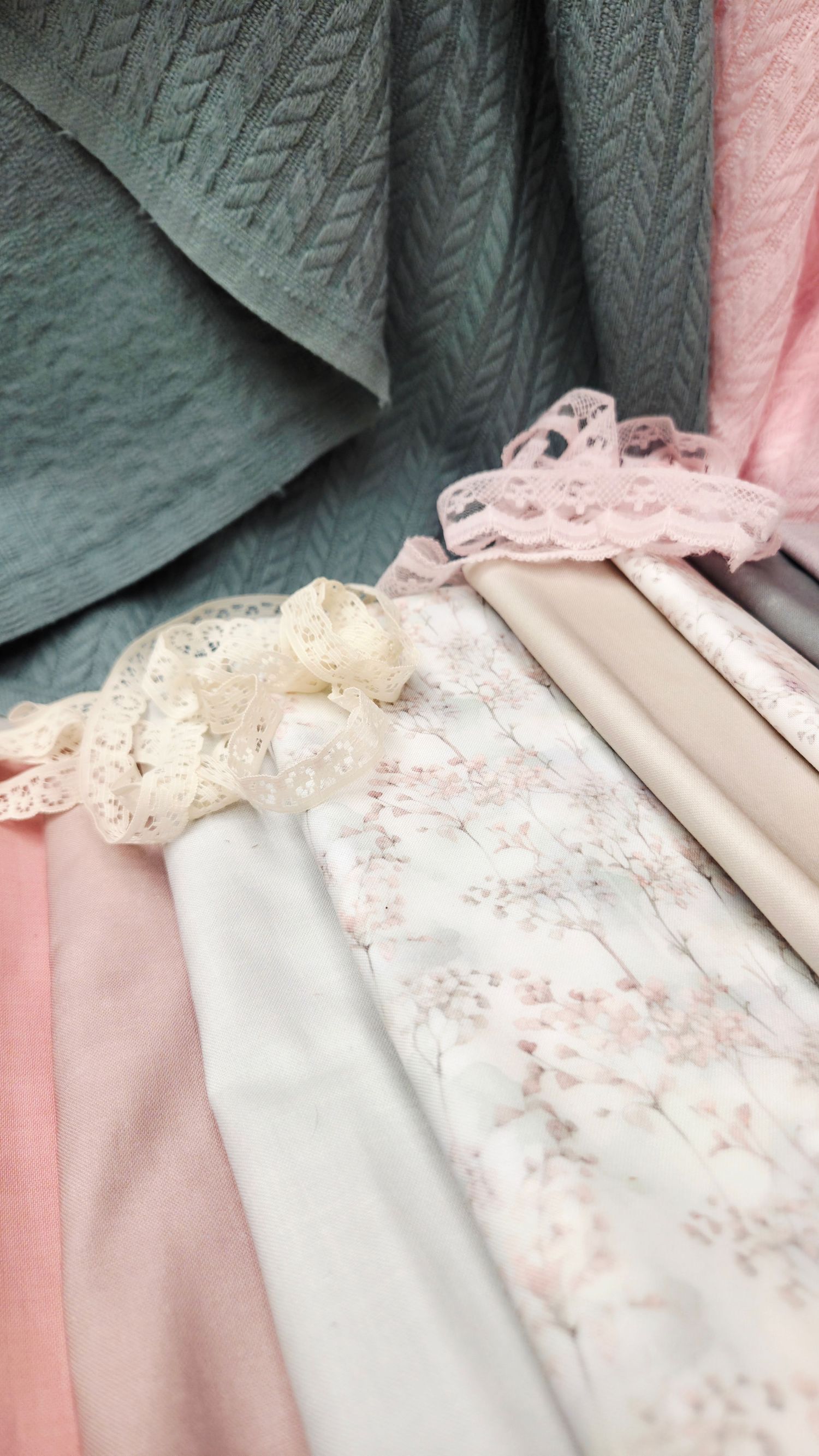 Soft pink and sage green fabric swatches with delicate lace trim and floral details displayed together.