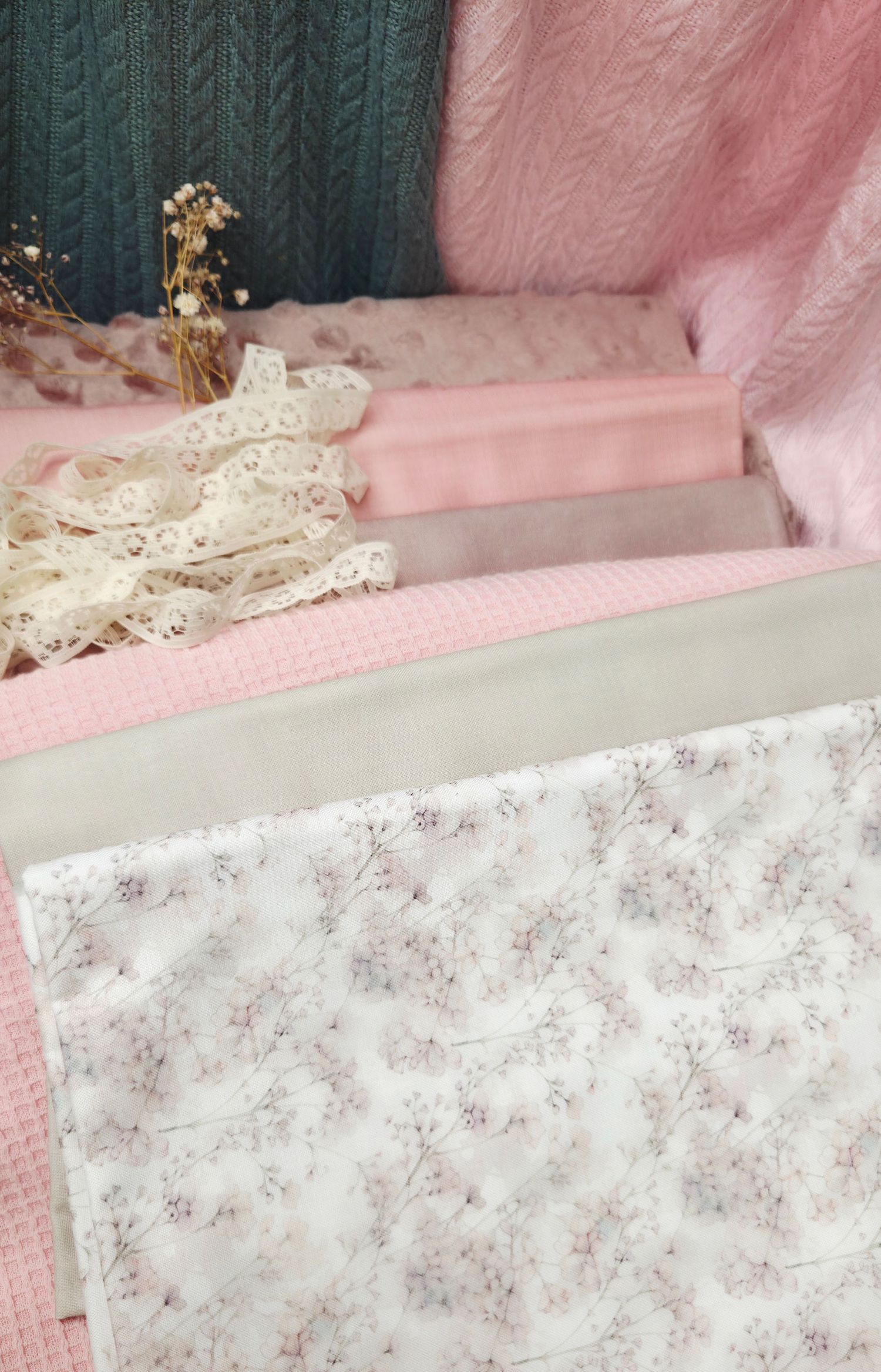 Soft pink and sage green fabric swatches with floral print and lace trim arranged in a cozy styled flat lay.