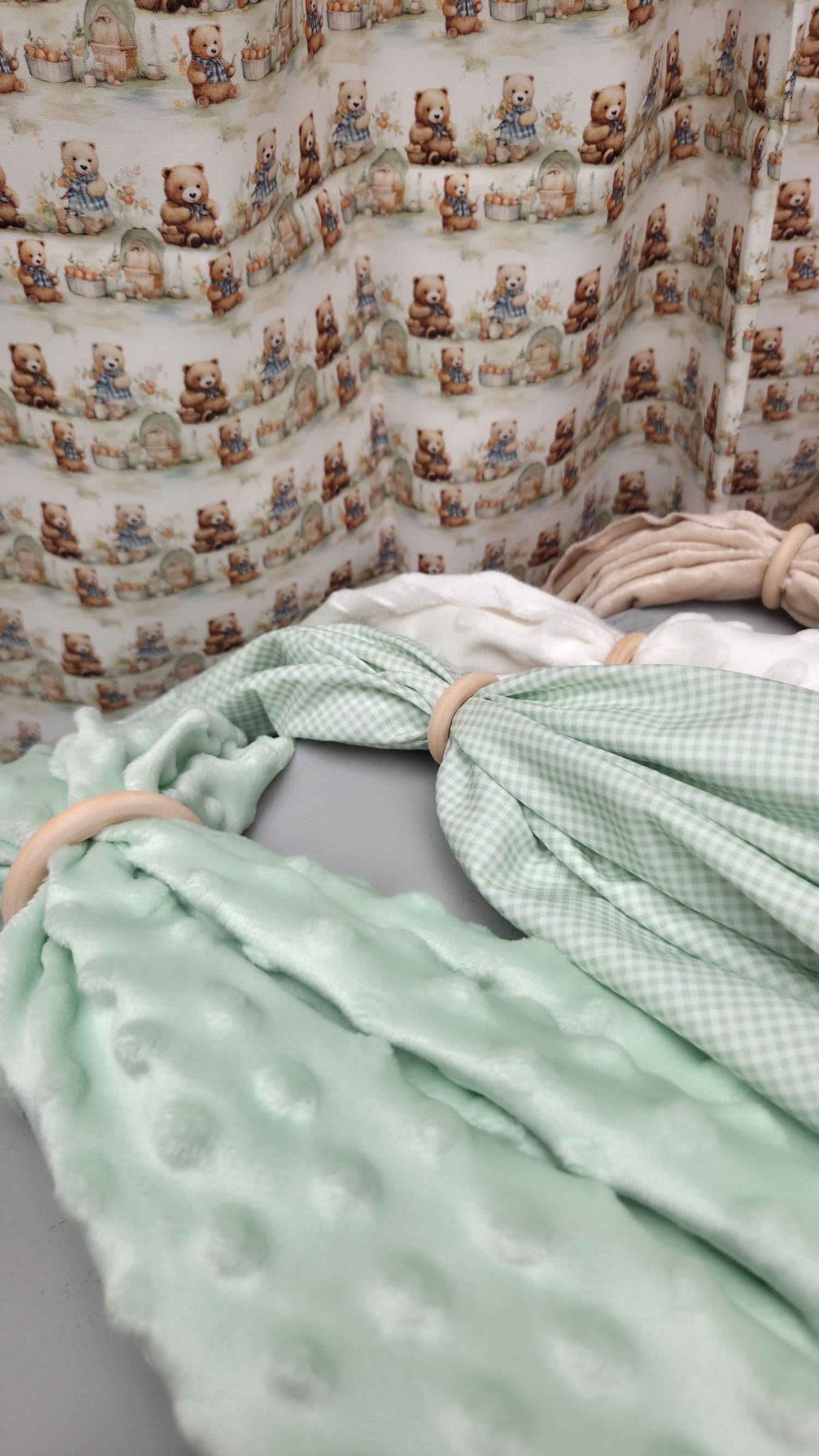 Green gingham and minky baby blanket set with wooden rings, displayed against teddy bear print nursery fabric backdrop.