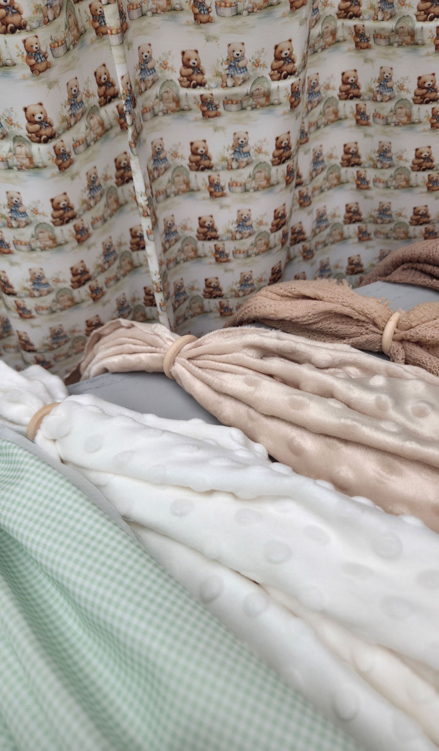 Baby crib bedding set featuring teddy bear print bumper pads with soft minky blankets in beige, white, and sage green gingham.