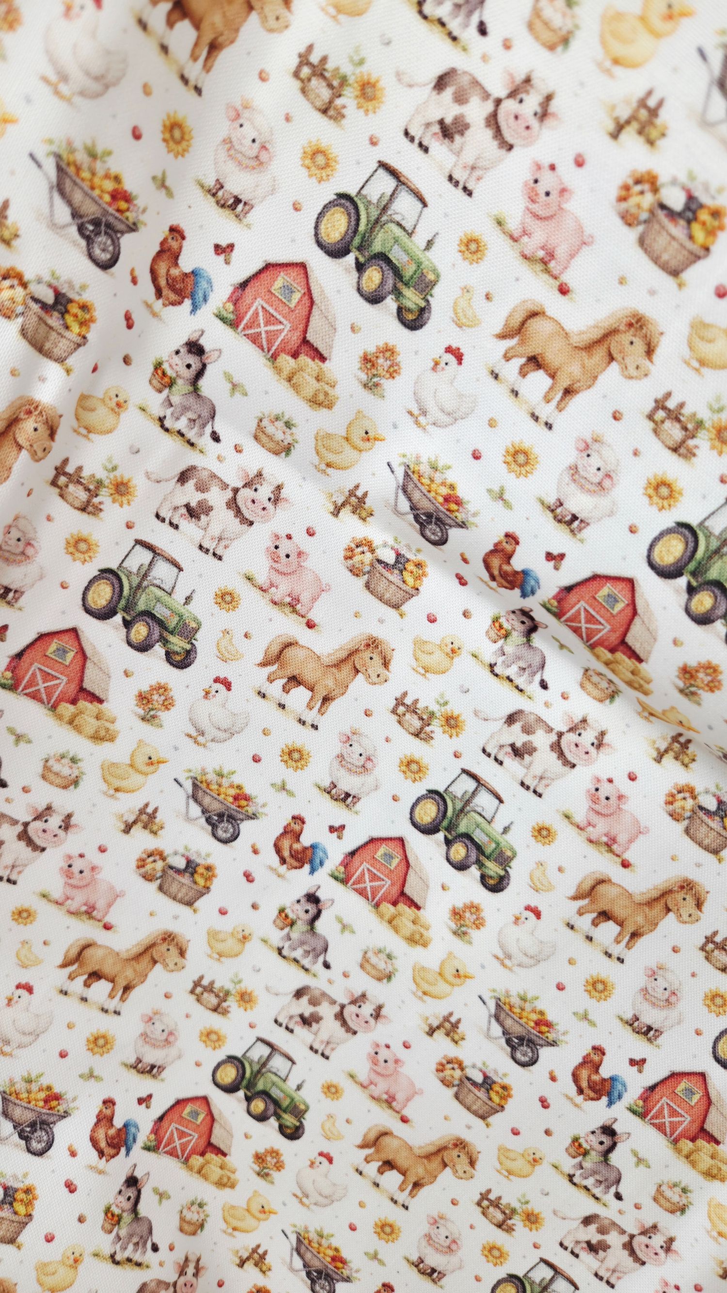 Charming farm animal fabric print featuring pigs, horses, cows, tractors, barns, and sunflowers on a white background.