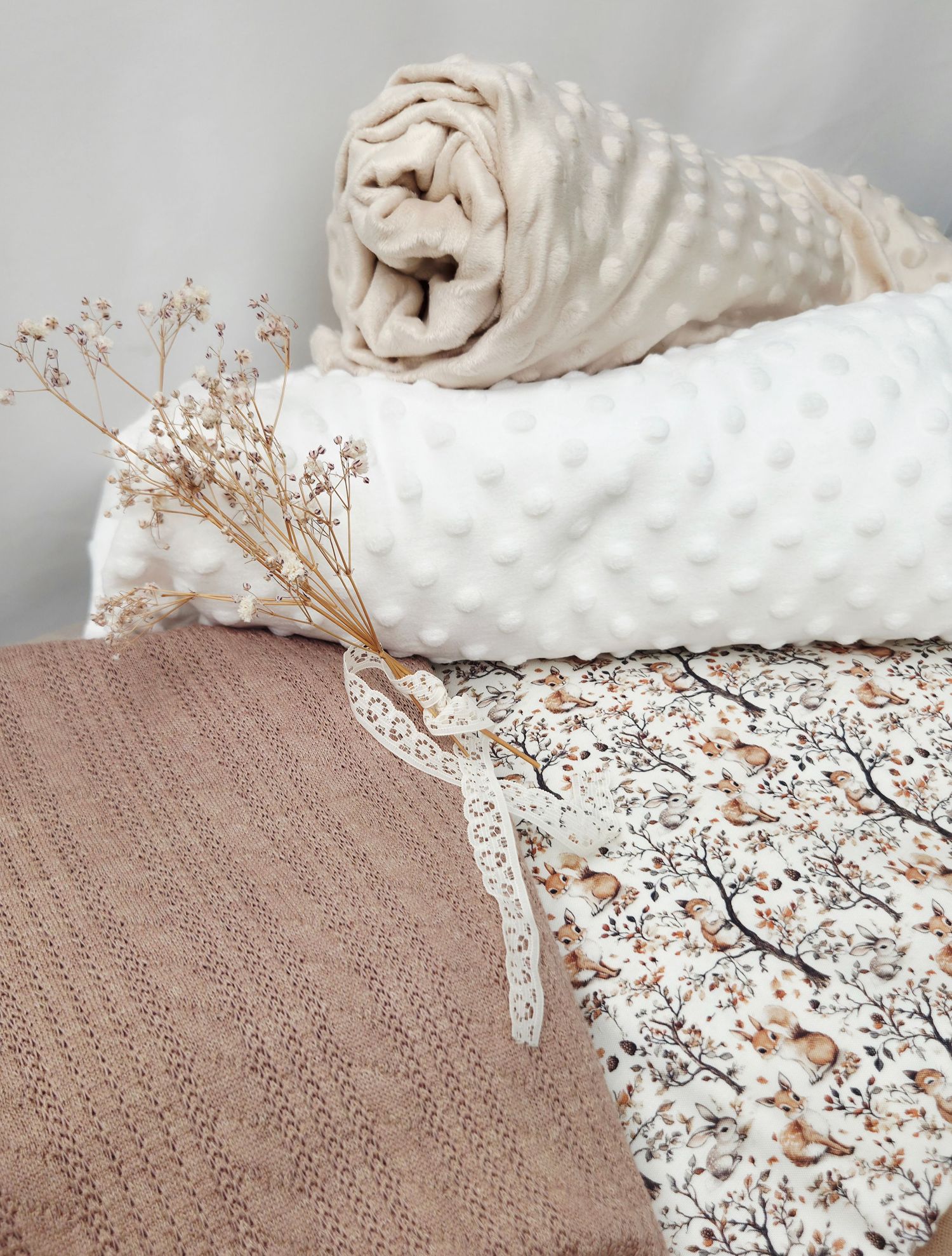 Cozy layered blankets with bubble texture, floral print, and knit fabric, styled with dried flowers in neutral tones.