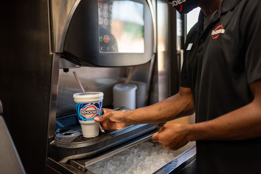 Employee fills a Rhodes cup at a self-serve fountain drink machine inside Rhodes store.
