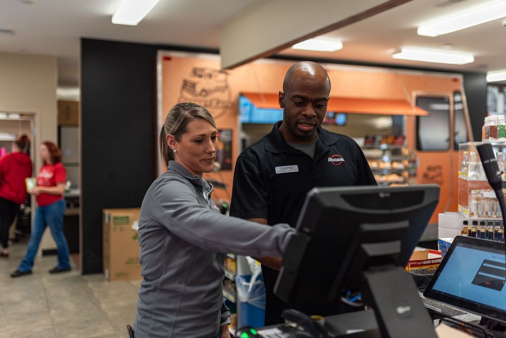 Two employees working together at a point-of-sale terminal in a modern fast-food restaurant.