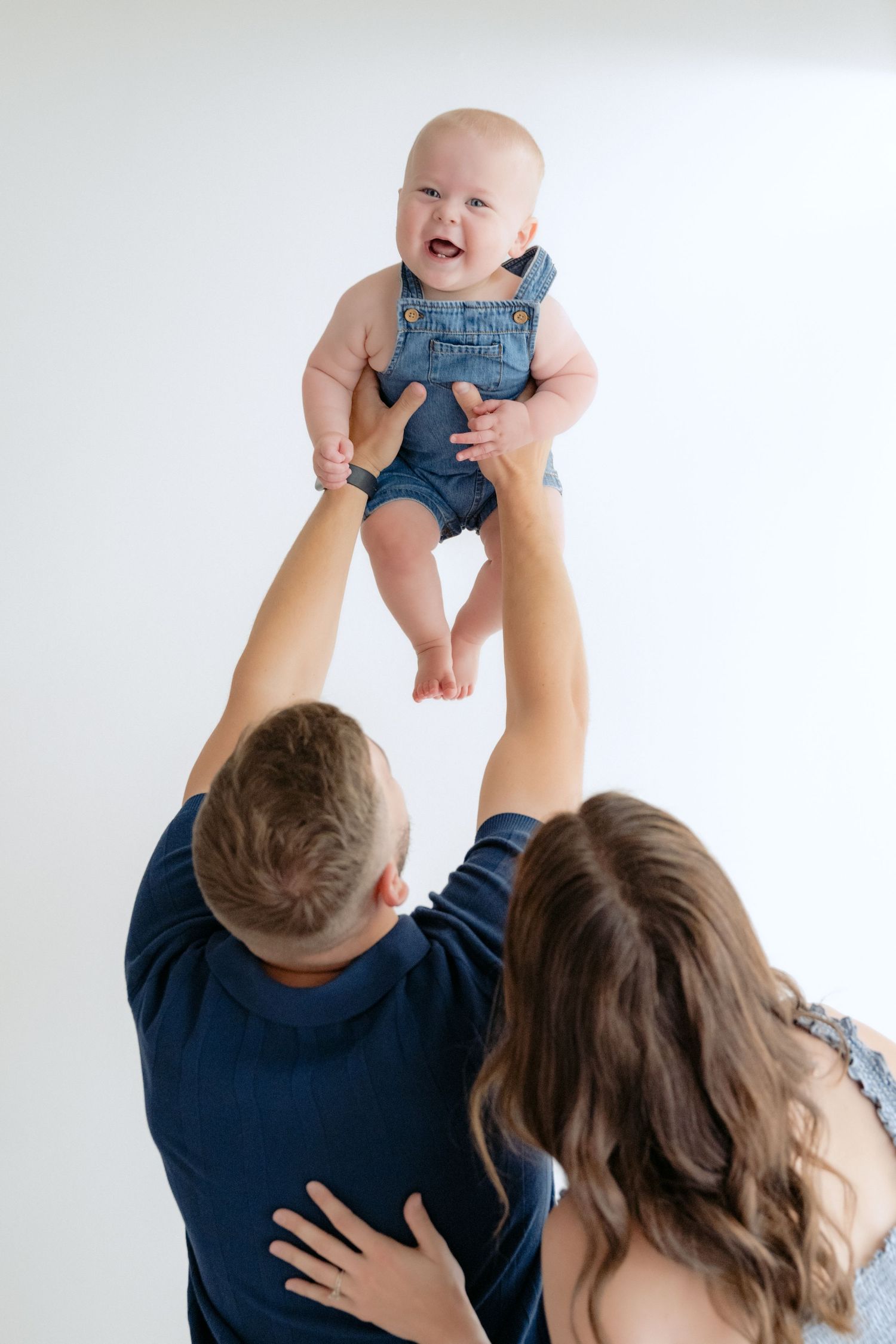 Parents throw baby up in the air during an in-studio family session in New Richmond, WI.