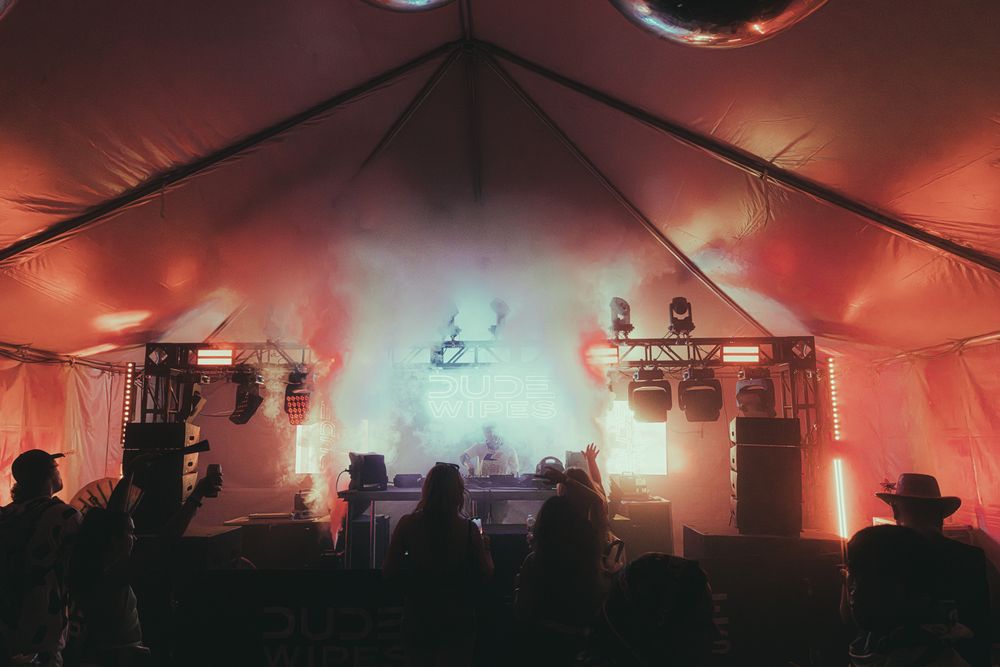Red and orange fog-filled festival tent stage with dramatic lighting and dancing crowd.