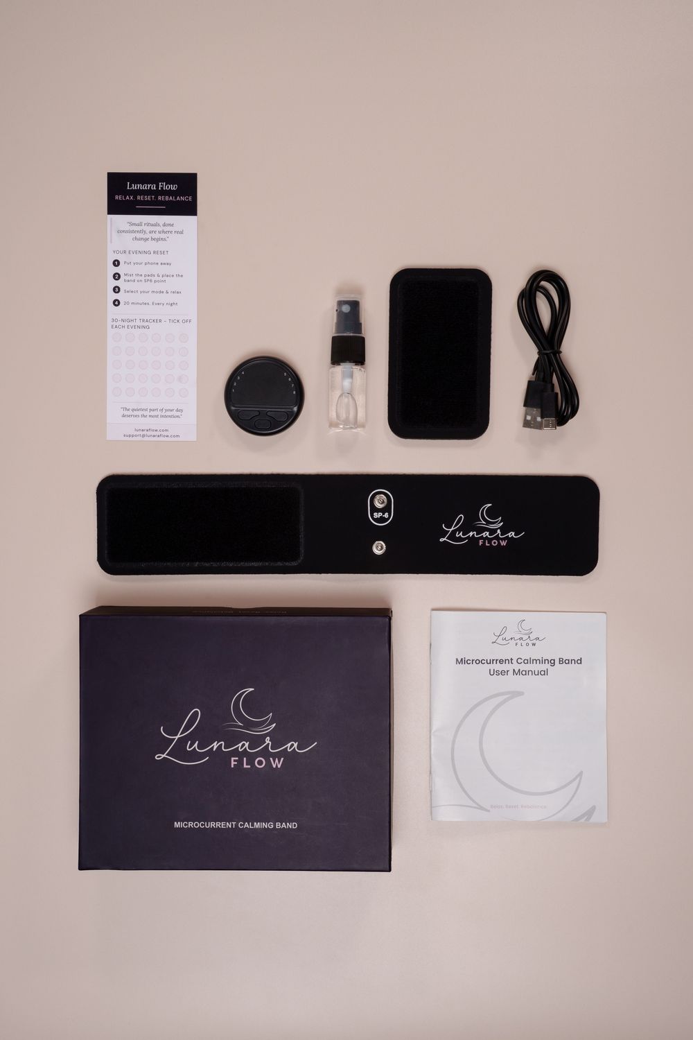Lunara Flow Microcurrent Calming Band complete kit with device, charger, accessories, and user manual on beige background.