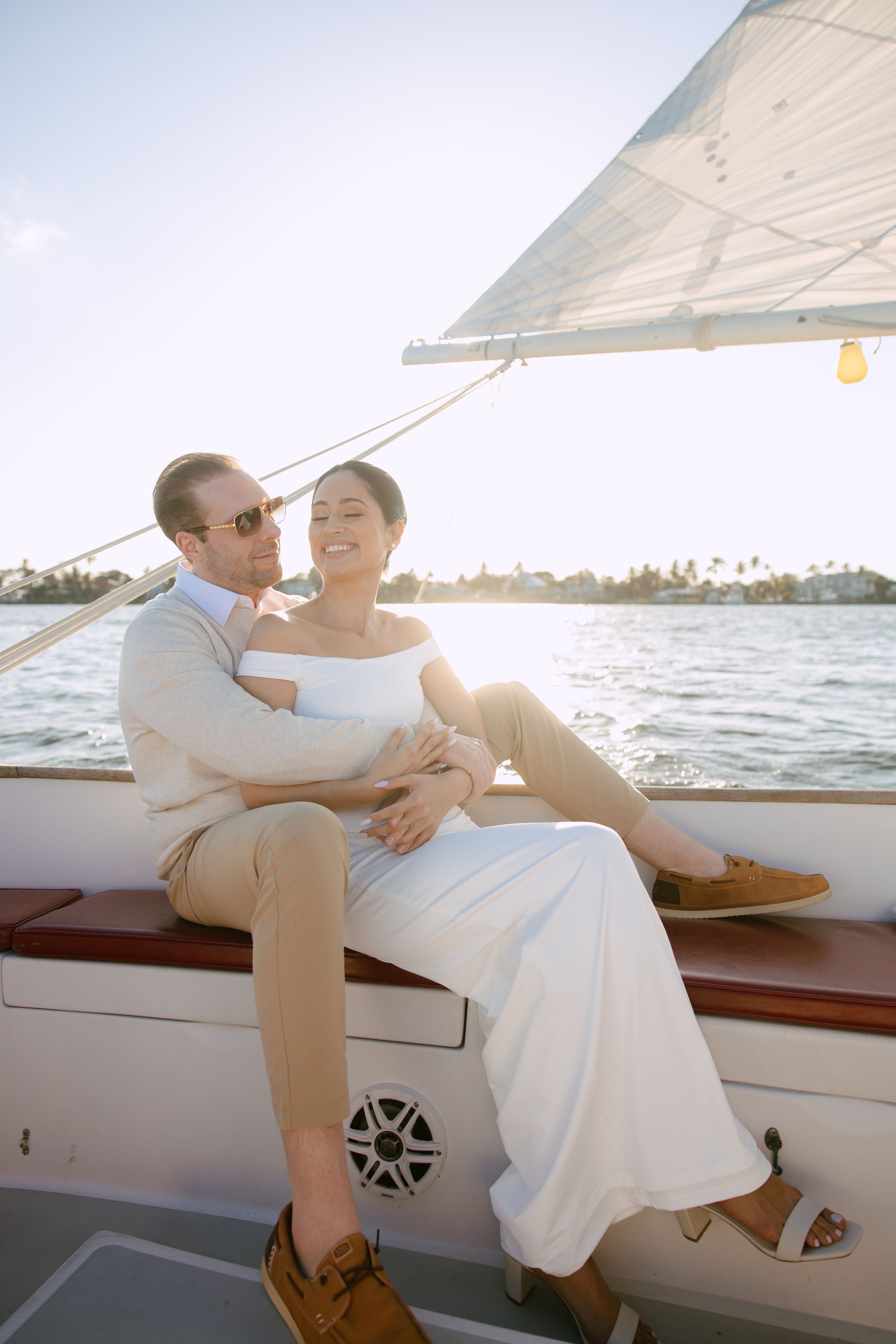Couple relaxing together on a sailboat deck, bathed in warm sunset light on the water.