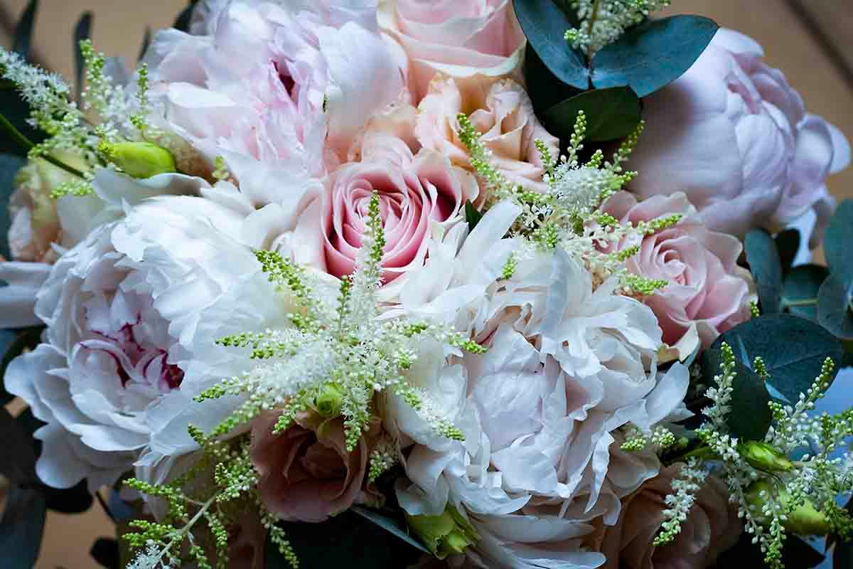 Elegant bridal bouquet featuring soft pink roses, white peonies, and delicate astilbe flowers.