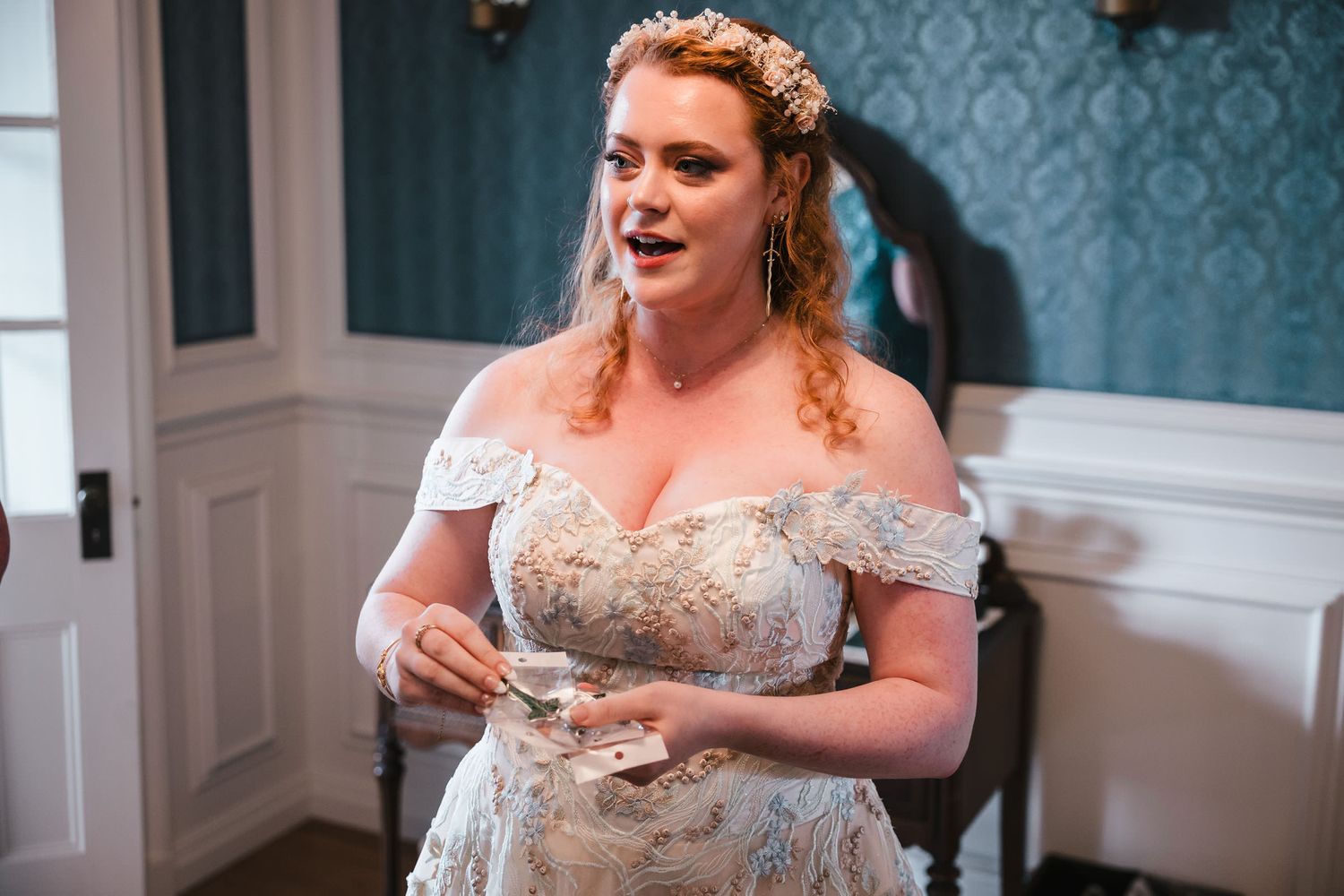 Bride greeting bridesmaids, holding a packaged elf leaf pin, explaining her gift to the bridal party at Searles Castle.