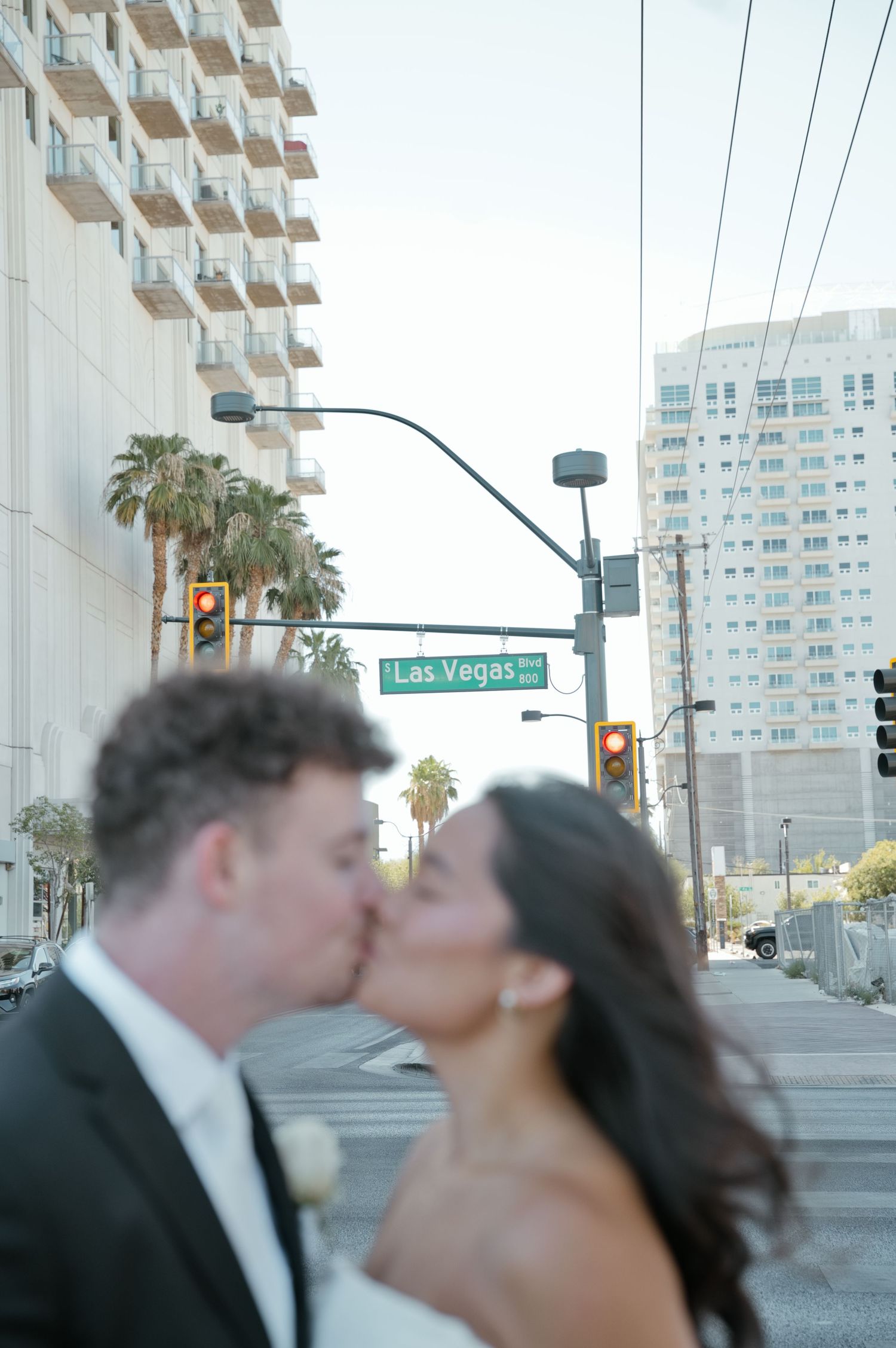 Newlywed couple sharing a romantic kiss on a Las Vegas street corner, bride in white gown and groom in suit.