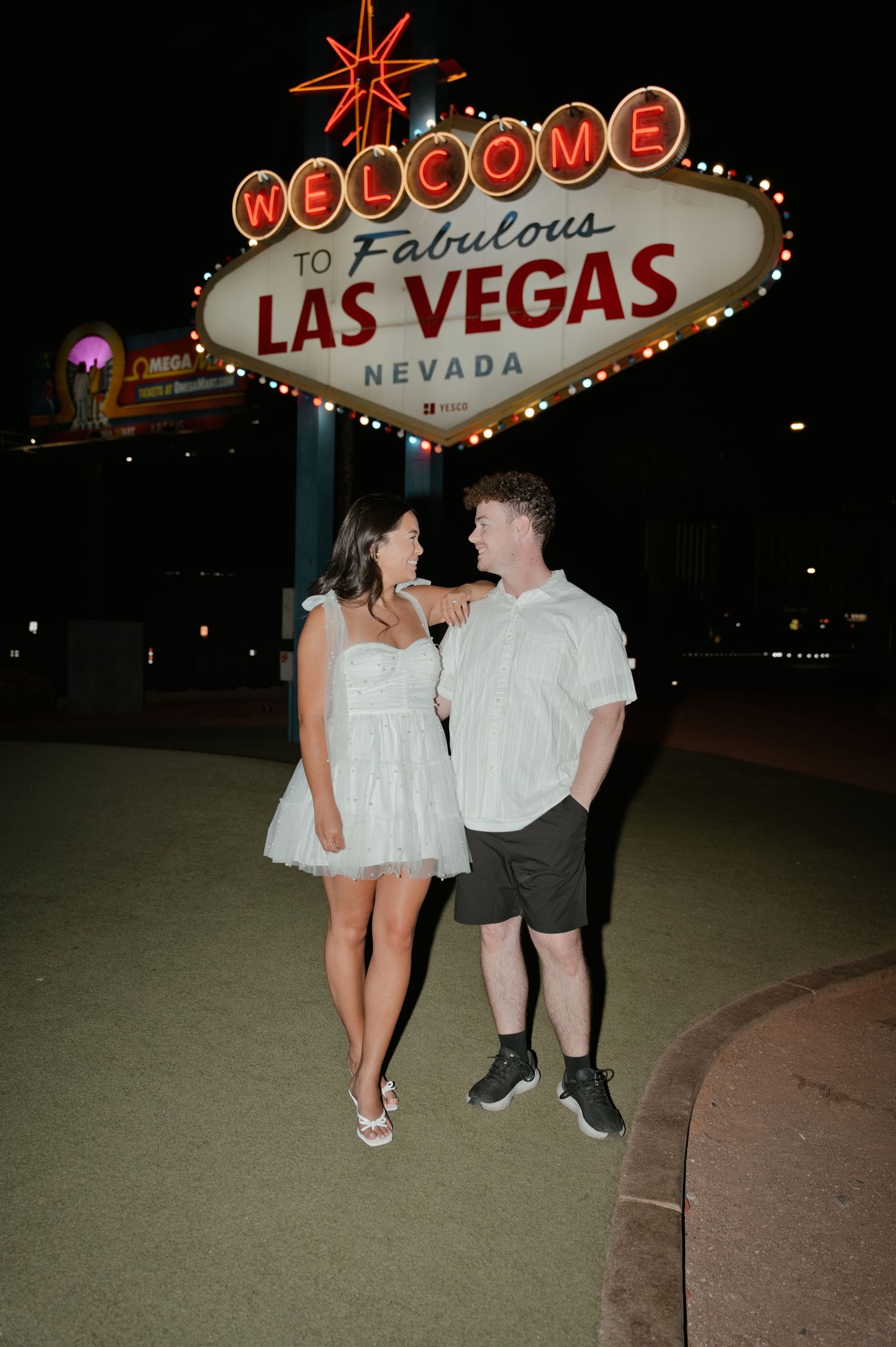 Couple posing in front of the iconic Welcome to Fabulous Las Vegas Nevada sign at night.