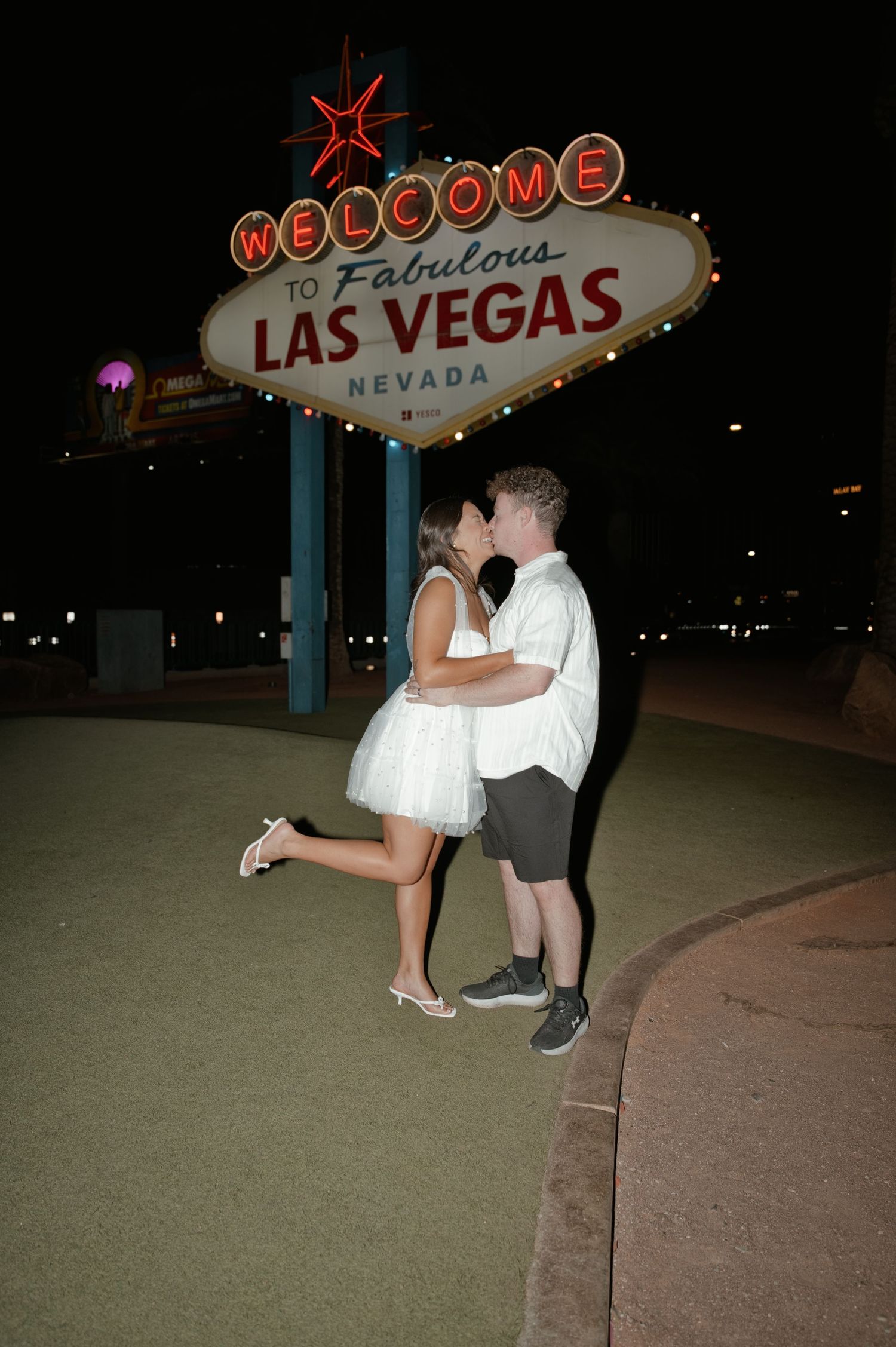 Couple kissing in front of the iconic Welcome to Fabulous Las Vegas Nevada sign at night.