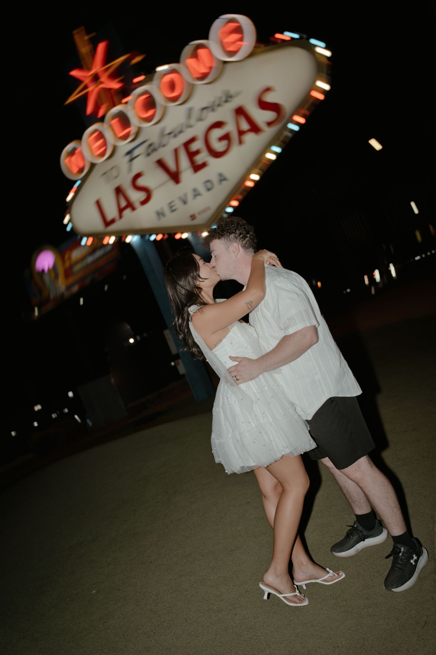 Couple kissing in front of the iconic Welcome to Fabulous Las Vegas Nevada sign at night.