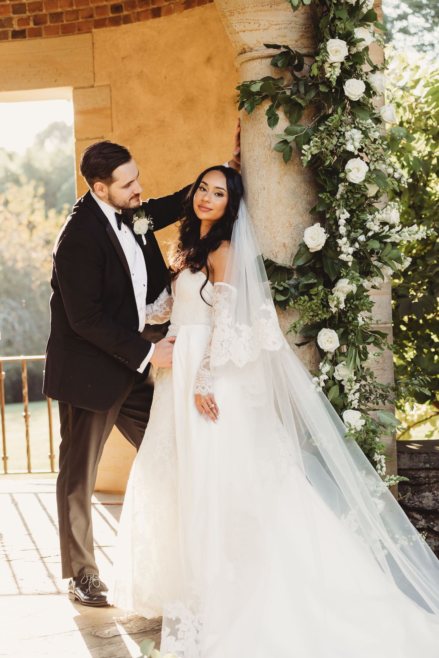Bride and groom sharing a kiss between ornate wrought iron gates, bride holding white bouquet in elegant wedding attire.
