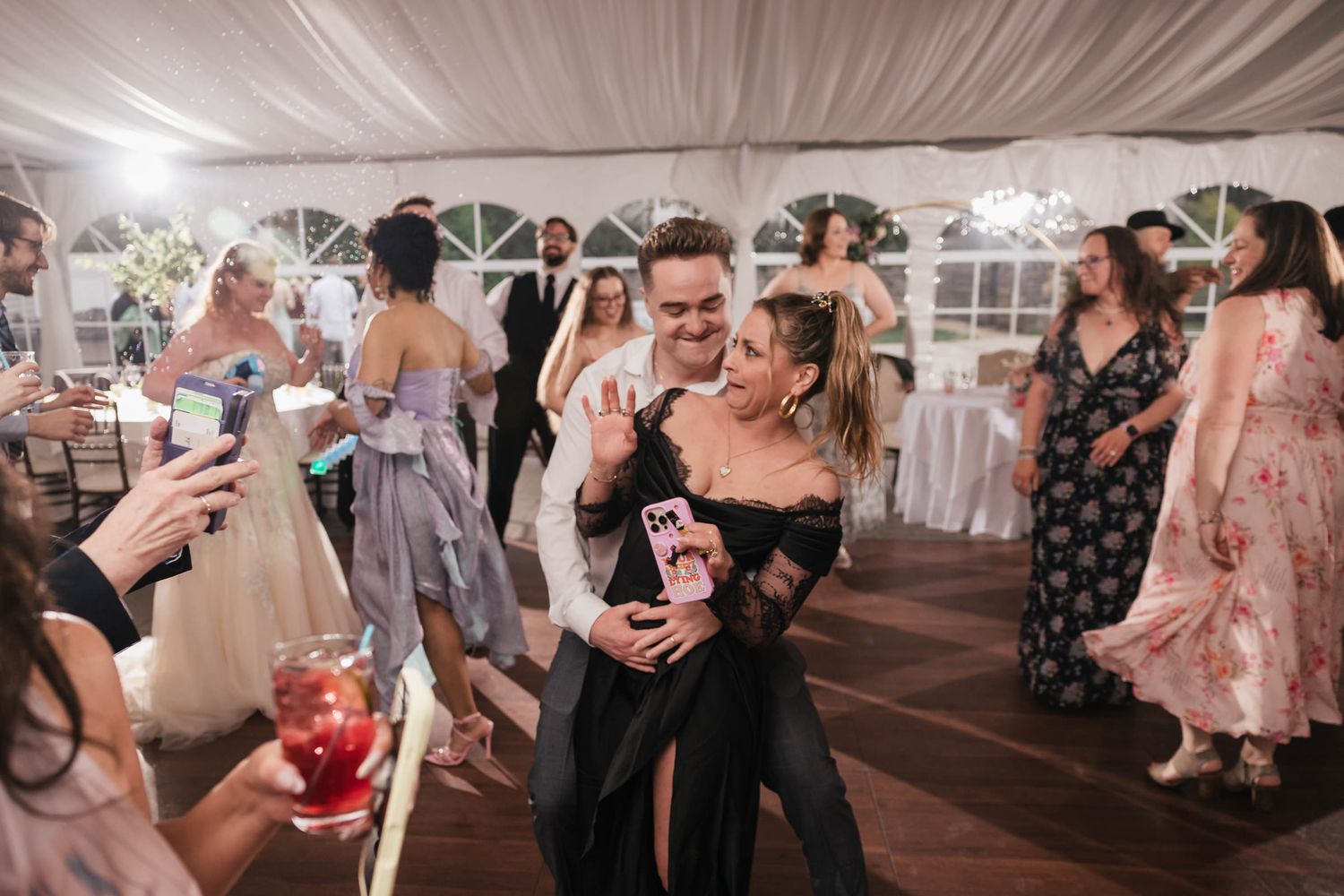 Two guests dancing closely together, one waving and smiling at the camera.