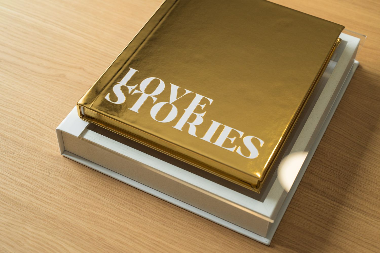 Gold metallic Love Stories hardcover book displayed on a white box on a wooden surface.