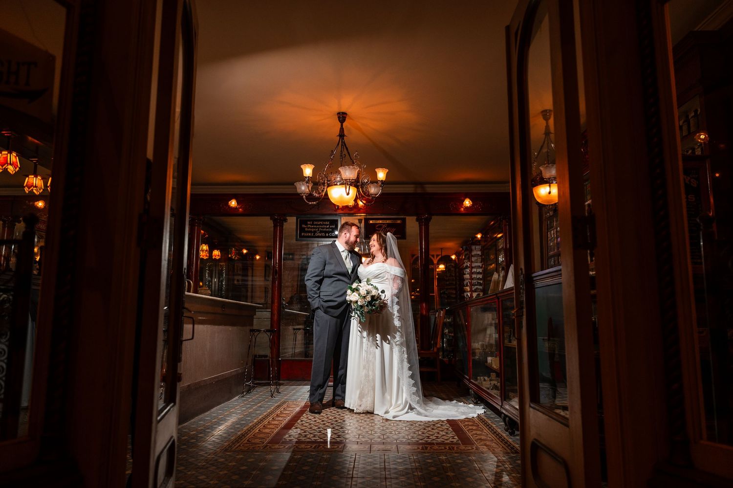 Bride and groom share a romantic moment in an elegant warmly lit venue doorway on their wedding day.