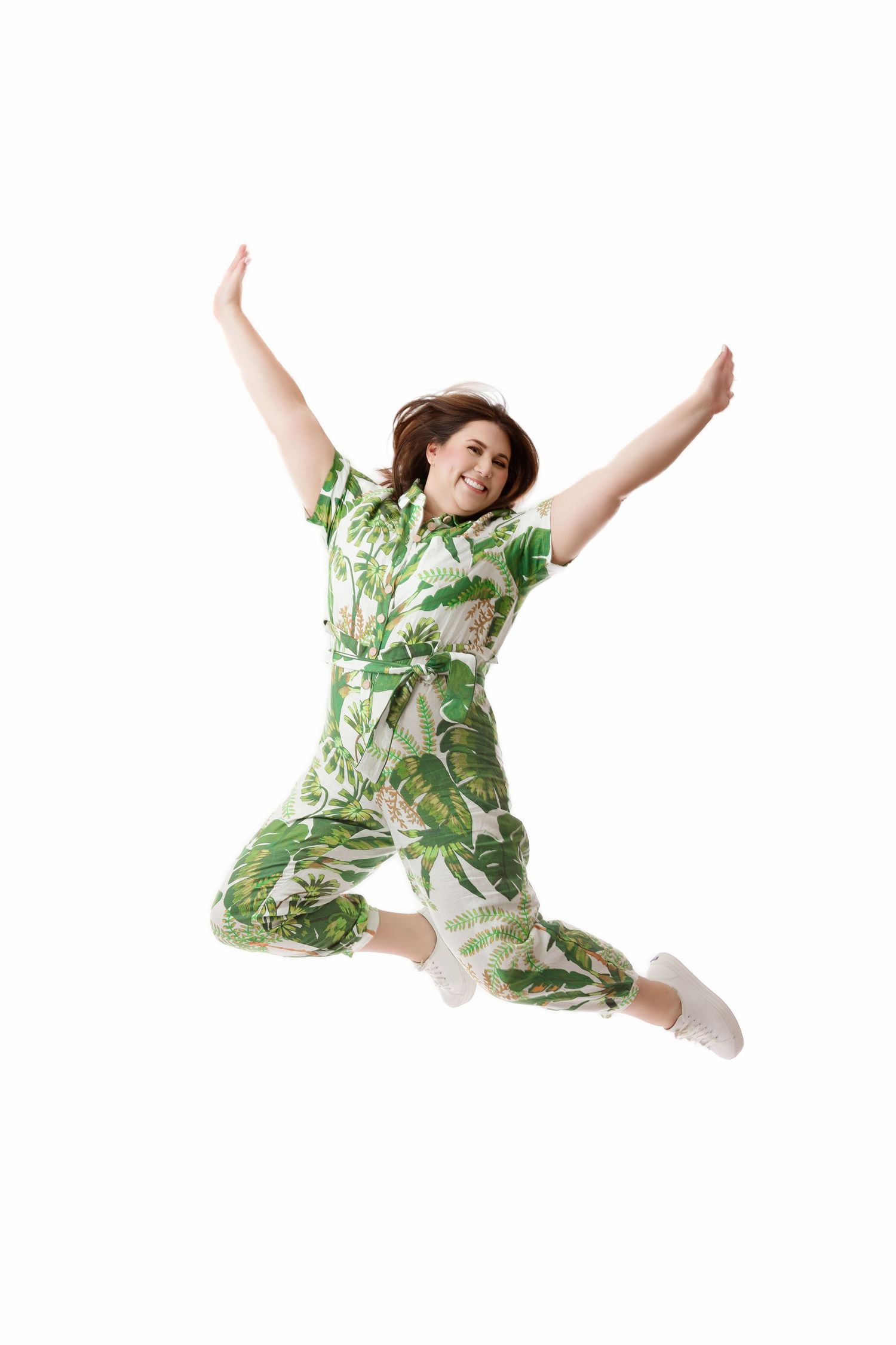 Miami personal branding portrait of a woman in a green botanical outfit jumping against a bright white background.
