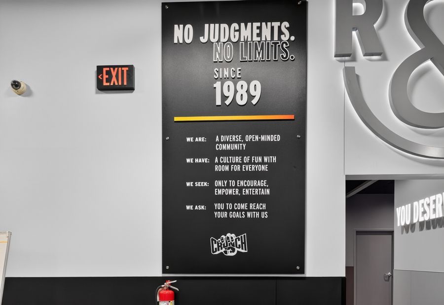Crunch Fitness motivational wall sign displaying No Judgments No Limits Since 1989 brand values poster.