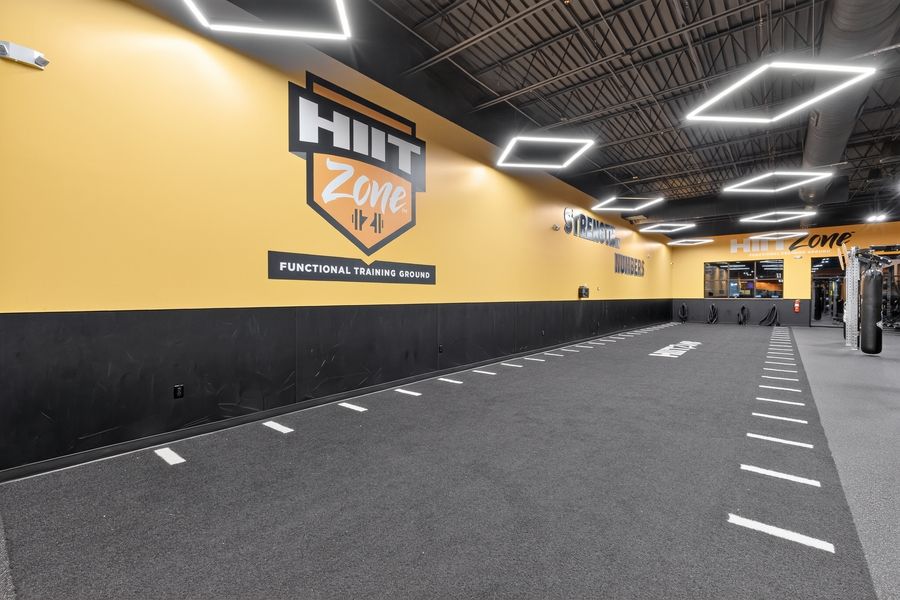 HIIT Zone functional training facility with yellow walls, turf lanes, and modern lighting in a spacious gym.