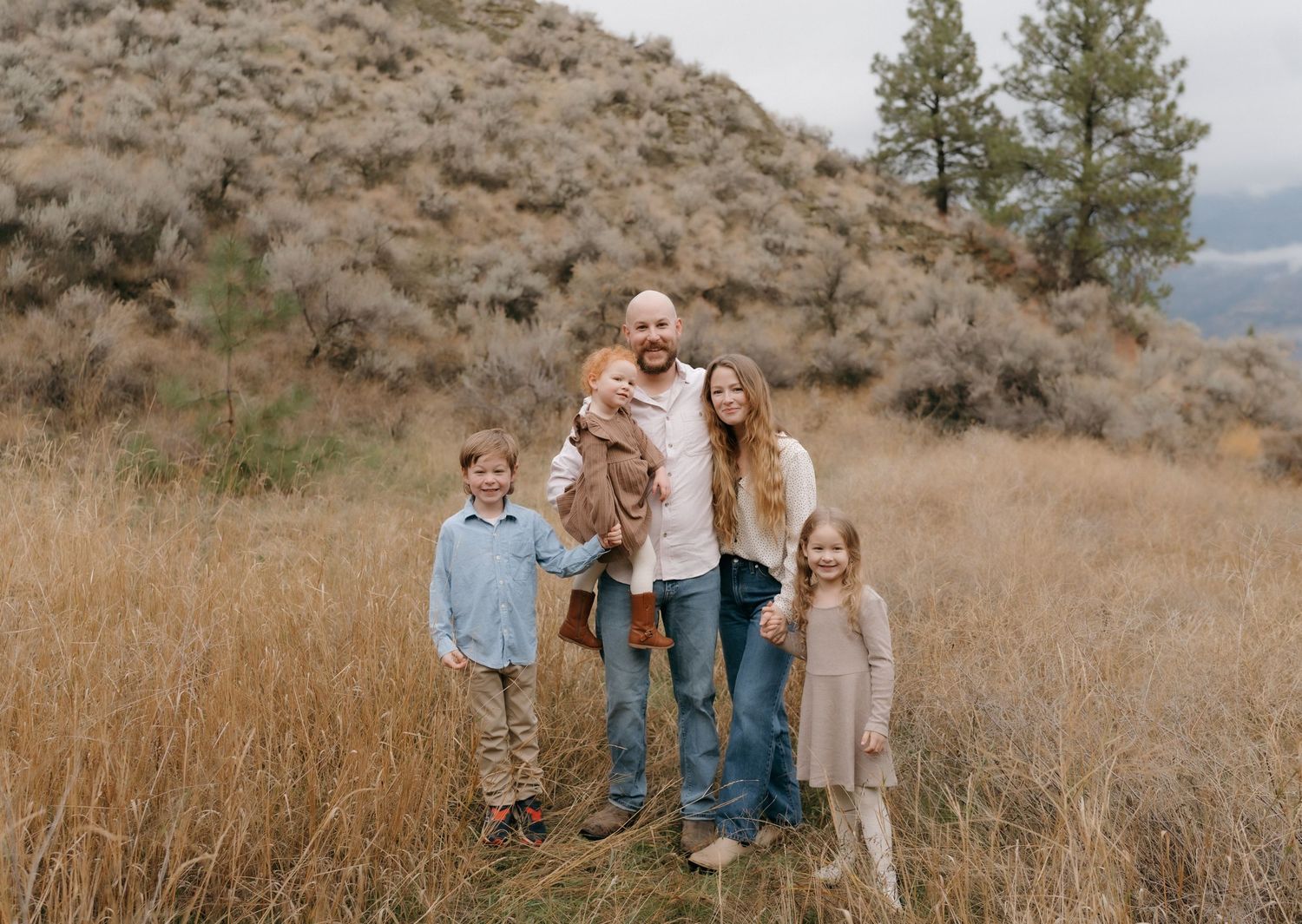 a family of five standing on a rock, behind them is the Rocky Mountains and a river,