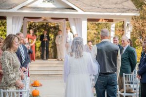 Outdoor wedding reception setup with white draped decor and guests mingling.