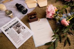 Wedding details including invitation and flowers arranged on rustic wooden surface.