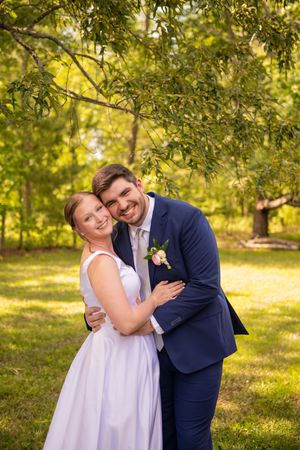 Wedding couple embracing in a sunlit garden setting during golden hour.