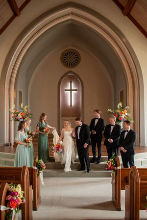 Wedding ceremony in a church with vaulted ceilings and floral arrangements.