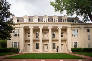 Exterior view of a grand white colonial-style building with columns and dormer windows.