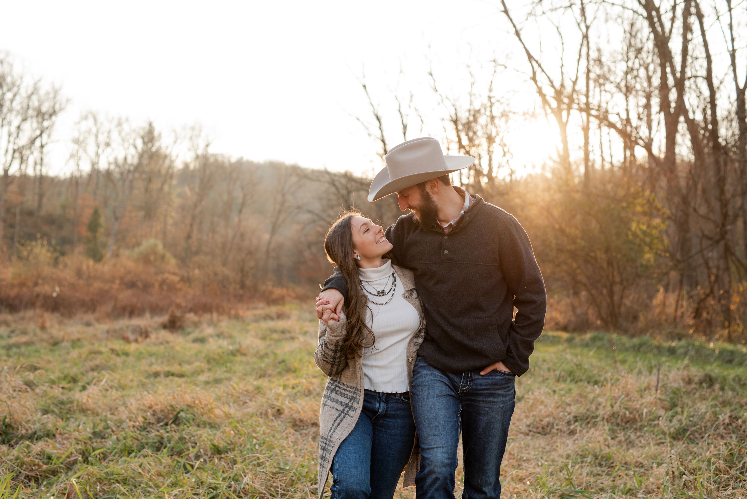 Couple shares intimate moment together outdoors during golden hour in autumn setting.
