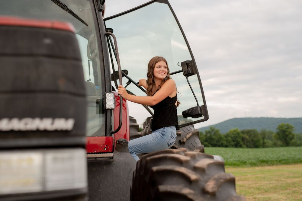 Person operating red Magnum tractor in rural field with mountains visible in background.