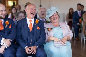 Parents of the bride on her wedding day laughing at the wedding ceremony