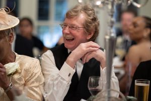 Candid image of the father of the bride laughing at speeches on their daughters wedding day