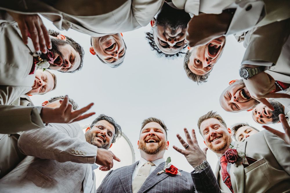 Low angle view of people forming a circle and smiling down at camera with light background.