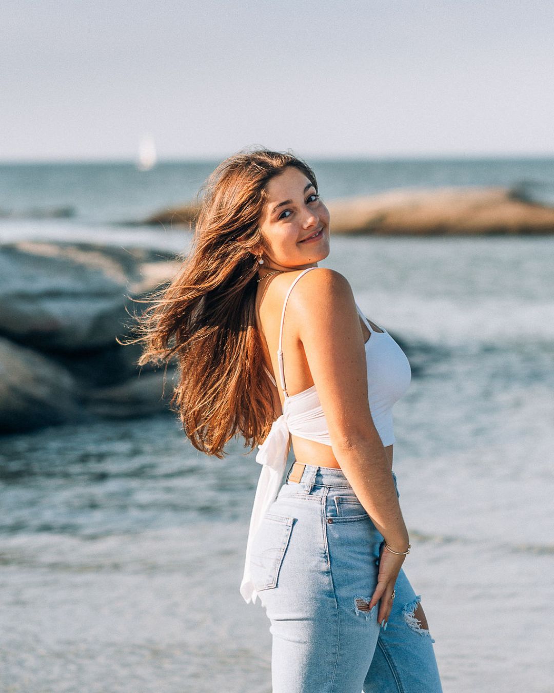 Casual beach portrait with ocean and rocks in background during golden hour.
