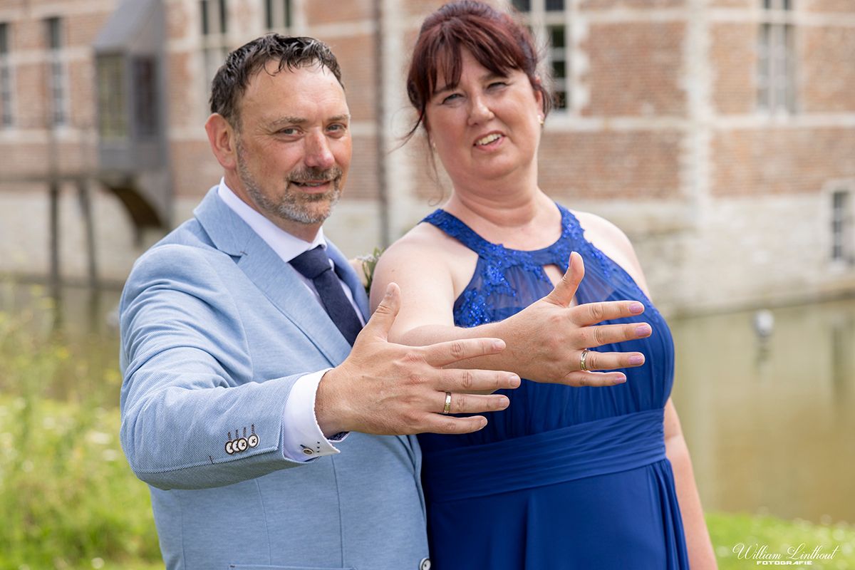 A couple shares a tender moment together outdoors near a brick building.