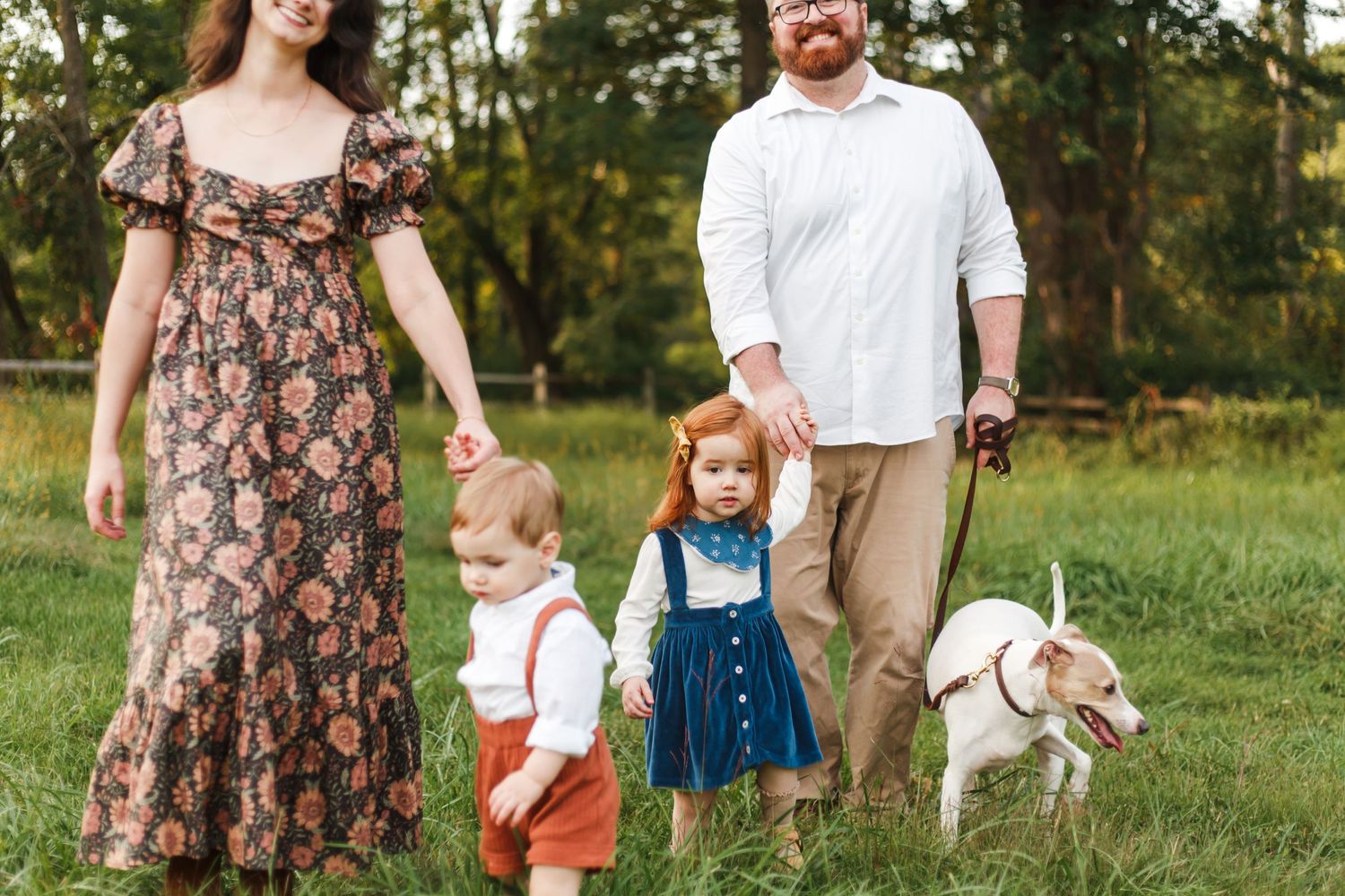 Family with children and dog pose together in casual attire on grassy field in Jockey Hollow Park Morristown NJ