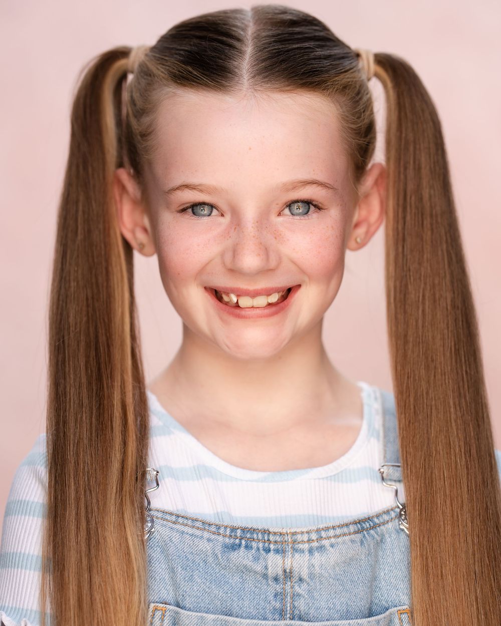 A series of four photos showing a child with pigtails making playful expressions against a pink background.