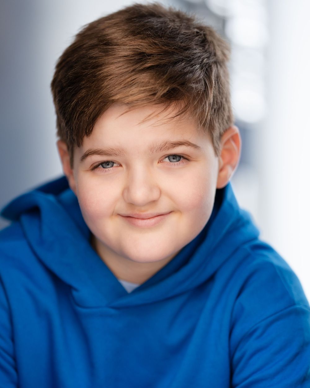 A series of four headshots showing a young person in a blue hoodie with varying expressions against a light background.