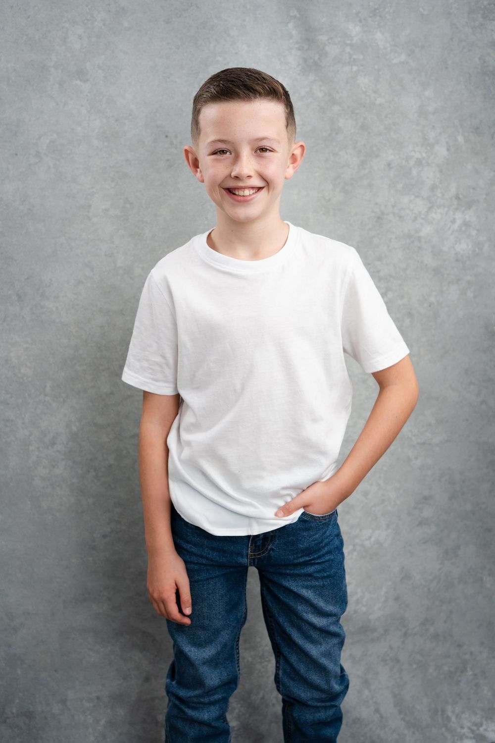Portrait series against grey backdrop showing casual white t-shirt and jeans combination.