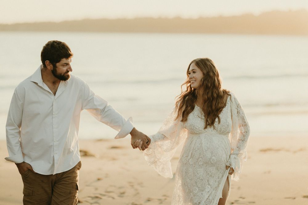 Candid moments of couple walking and embracing on beach at sunset.