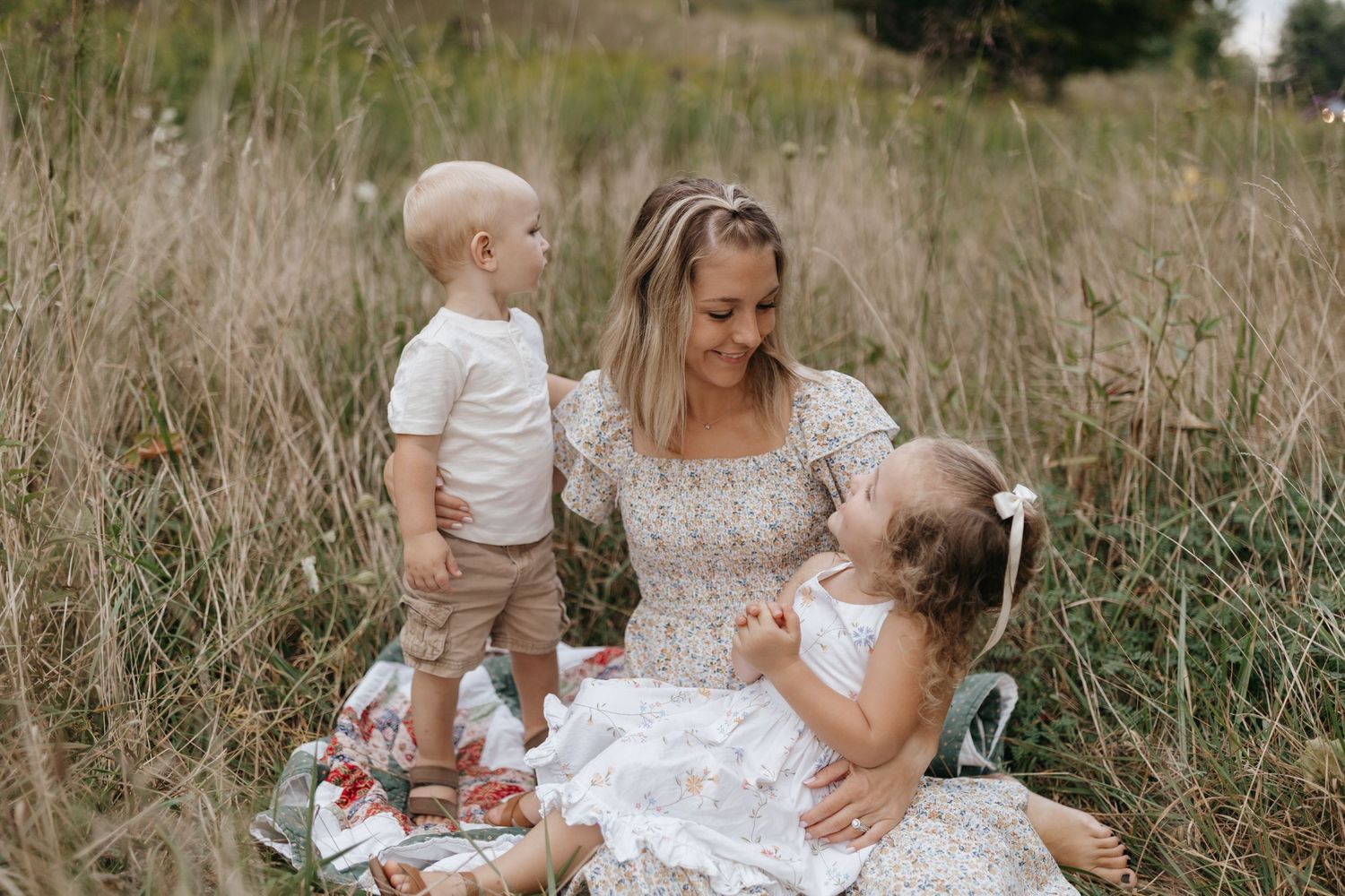 A summer family portrait in a field with children in white outfits.