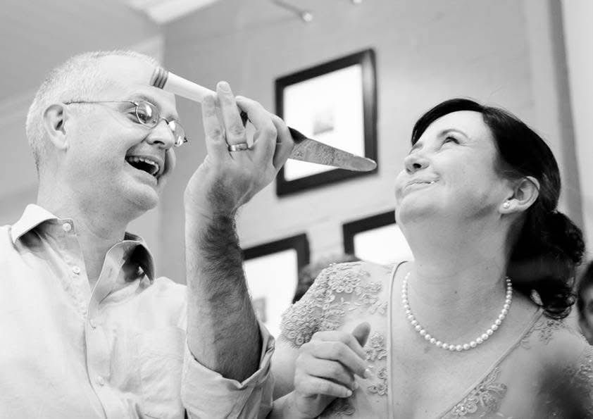 Black and white photo of laughing bride and groom sharing a fun moment indoors.