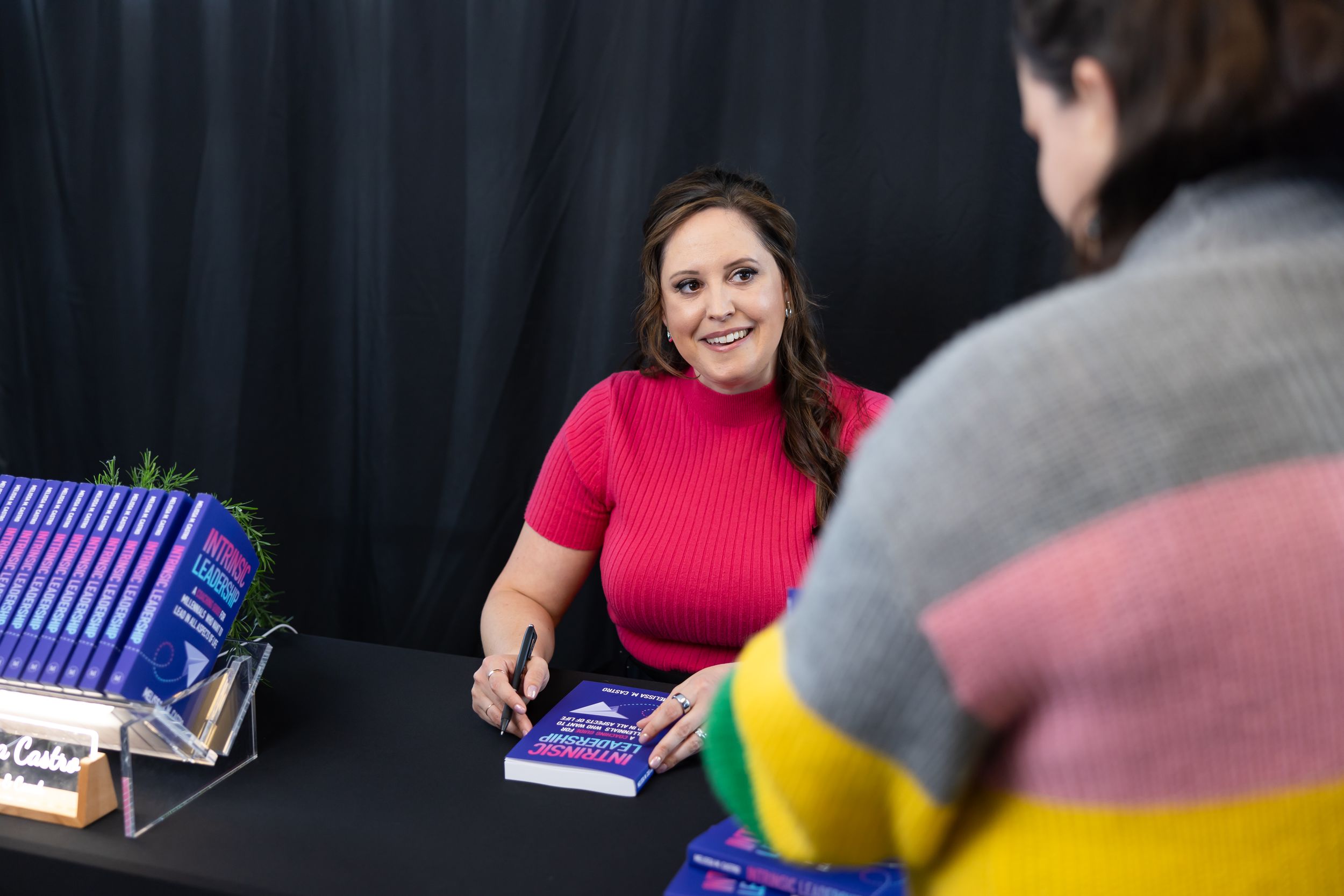 self published author Melissa Castro book signing event in Seattle, WA woman sitting at table signing book for millennial reader