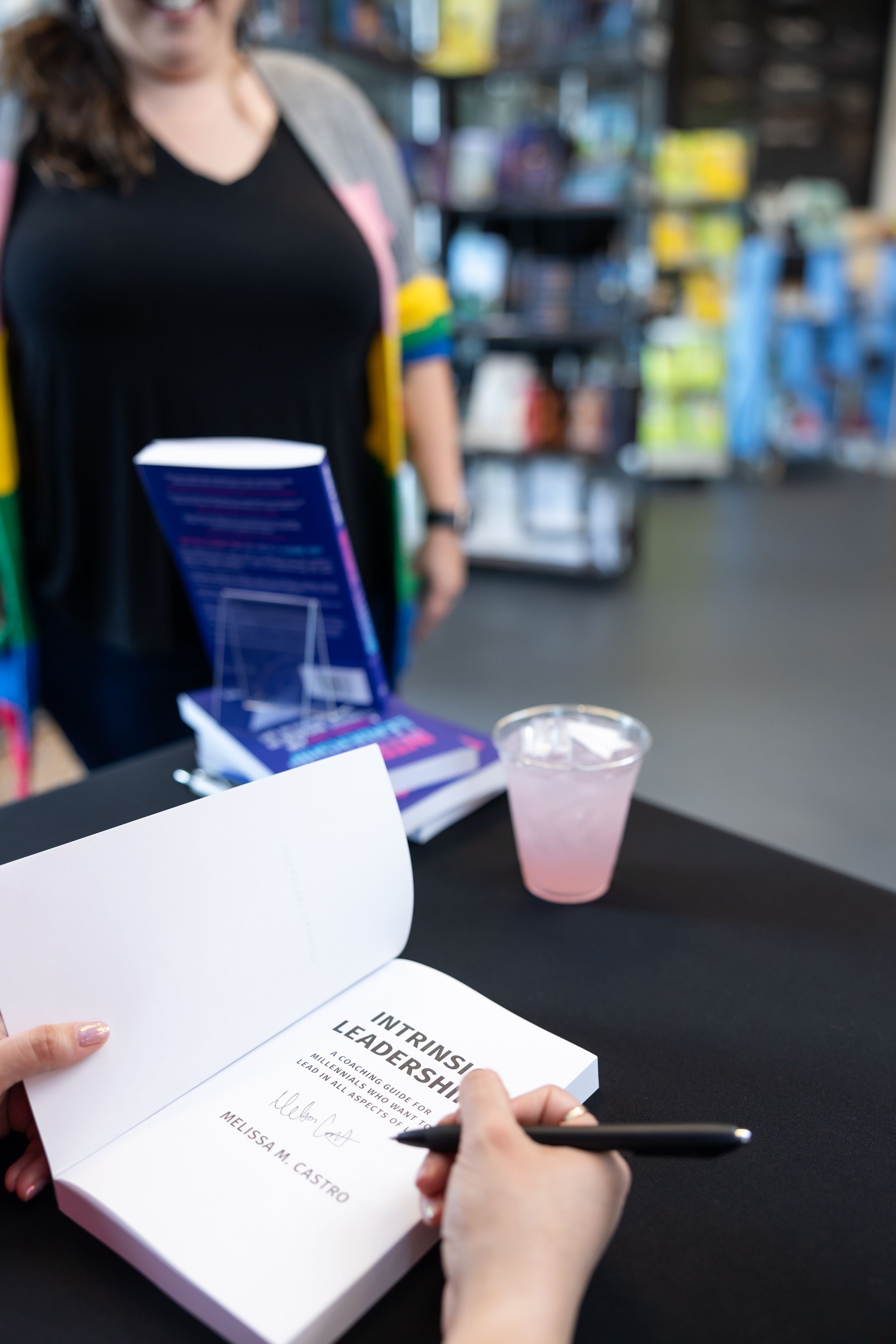 self published author Melissa Castro book signing event in Seattle, WA over shoulder author signing book on table for reader smiling