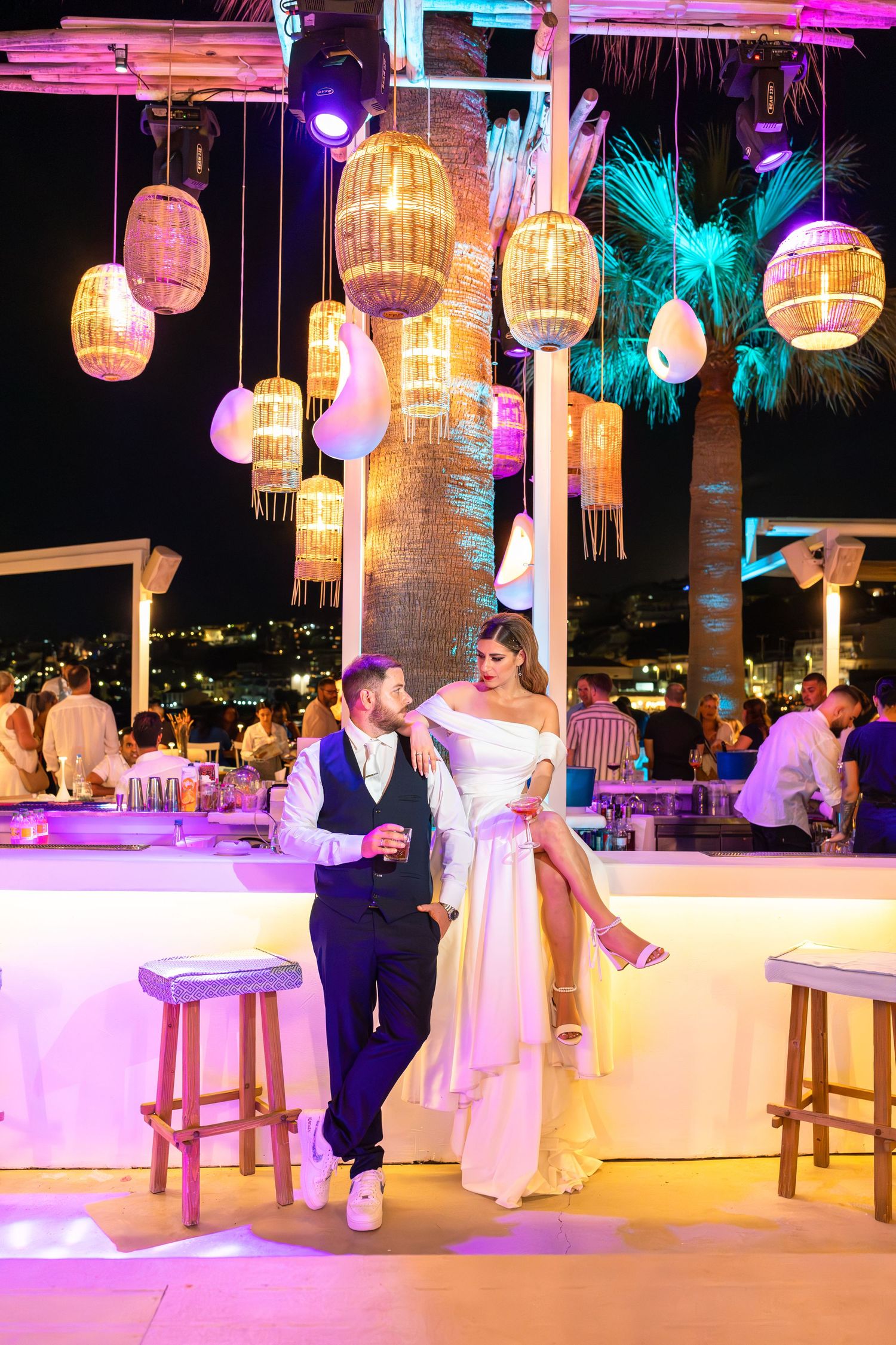 Couple at illuminated outdoor venue with hanging lanterns and colorful lighting.