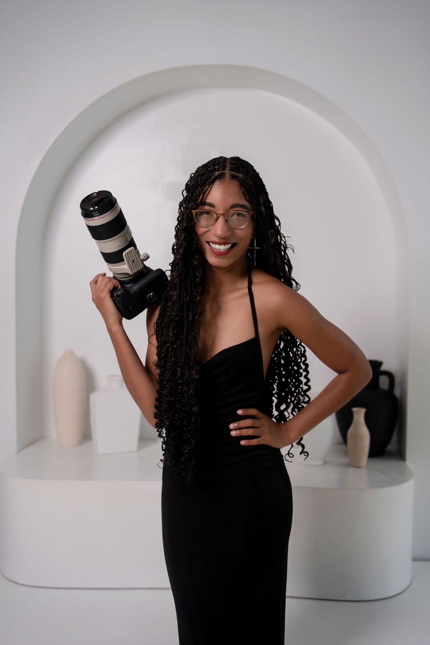 Creative portrait of photographer in orange dress holding camera on blue and gold background.